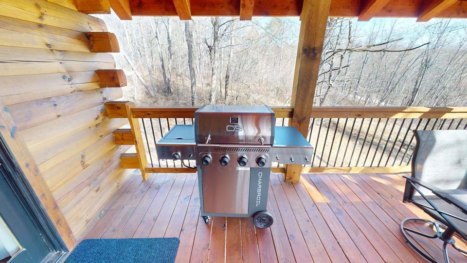 willifeesp-mar26-25 Open-concept living area with large windows showcasing forest views.